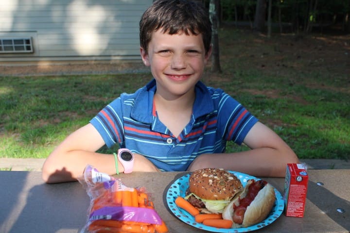 9 year old eating a hamburger and hotdog camping