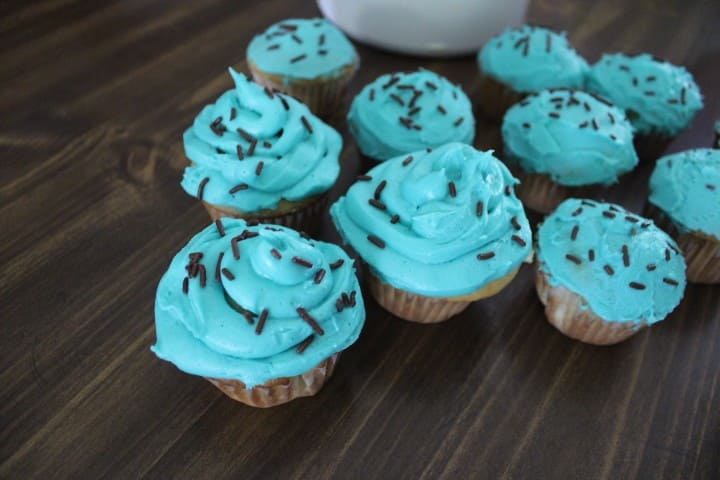 white cupcakes with teal frosting and black sprinkles