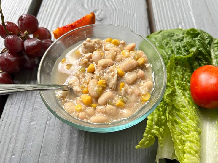 bowl of white chicken chili with lettuce and grapes