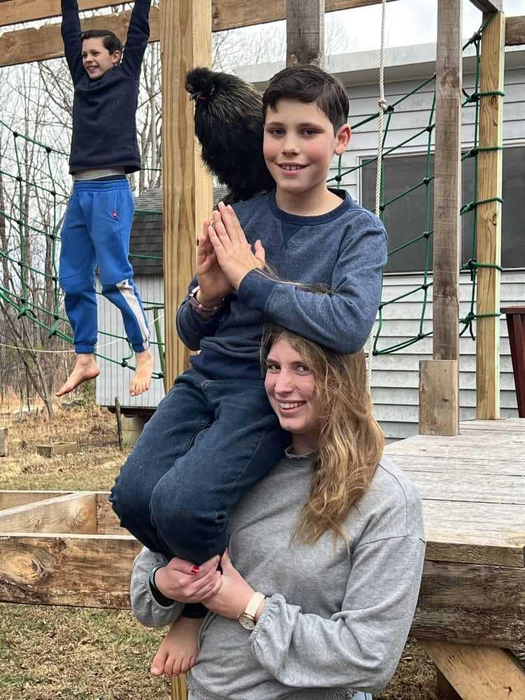 little brother doing shoulder angel on sister with a silkie on his shoulder