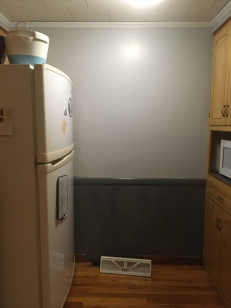 wood paneling and wall by fridge and microwave painted light and dark gray