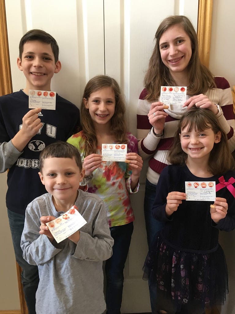 5 kids show cards how they typed their own blood in a memorable homeschool activity.