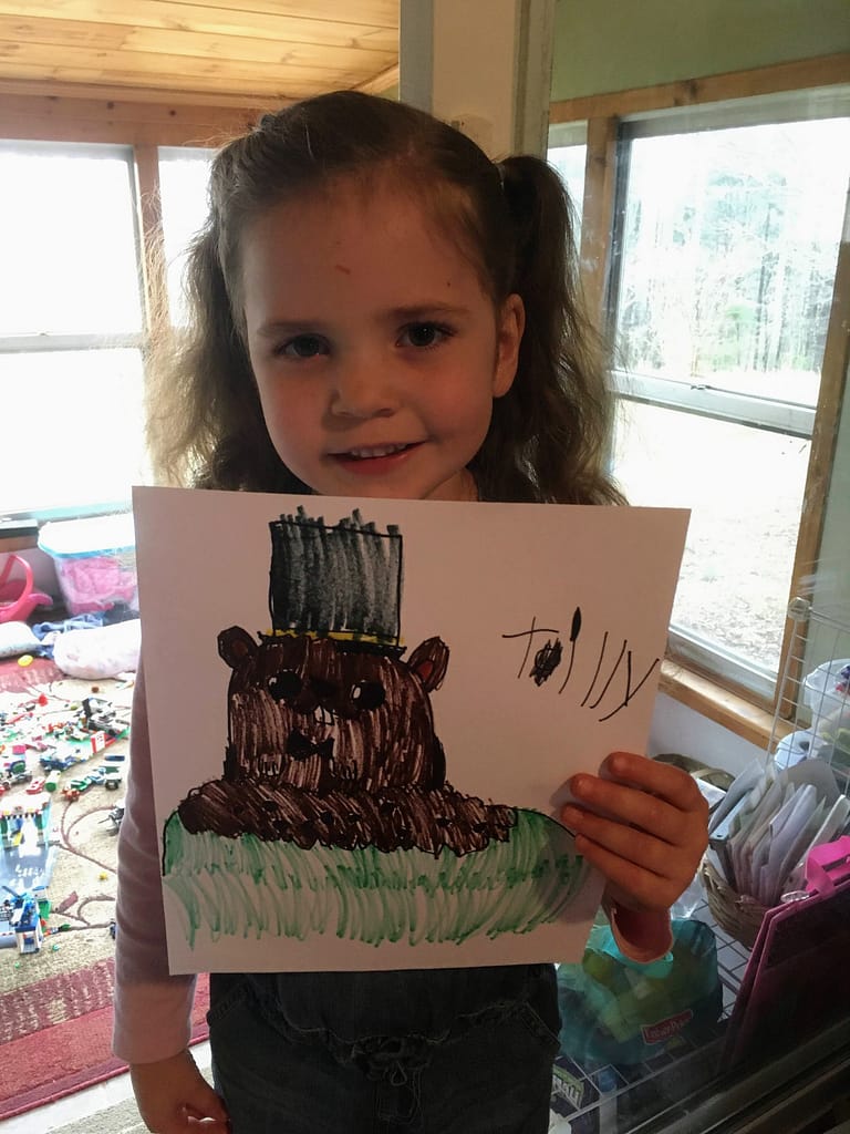 5 year old girl holding groundhog picture she drew