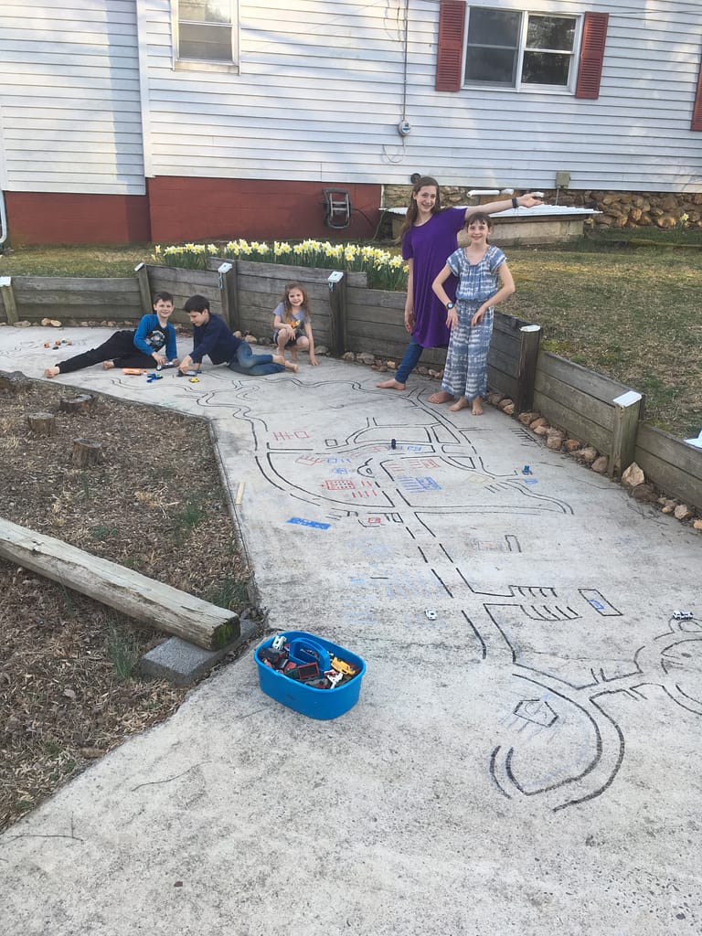 kids drawing roads on concrete for their toy cars