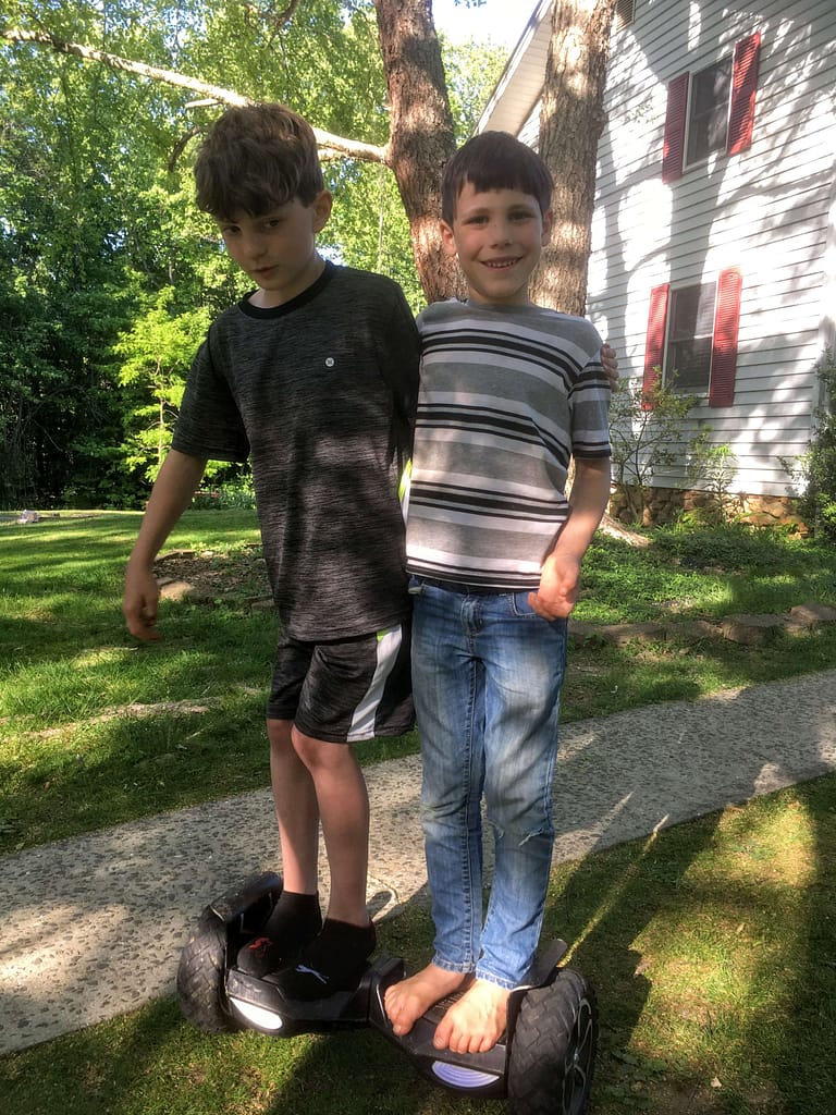 two boys riding on a hooverboard together
