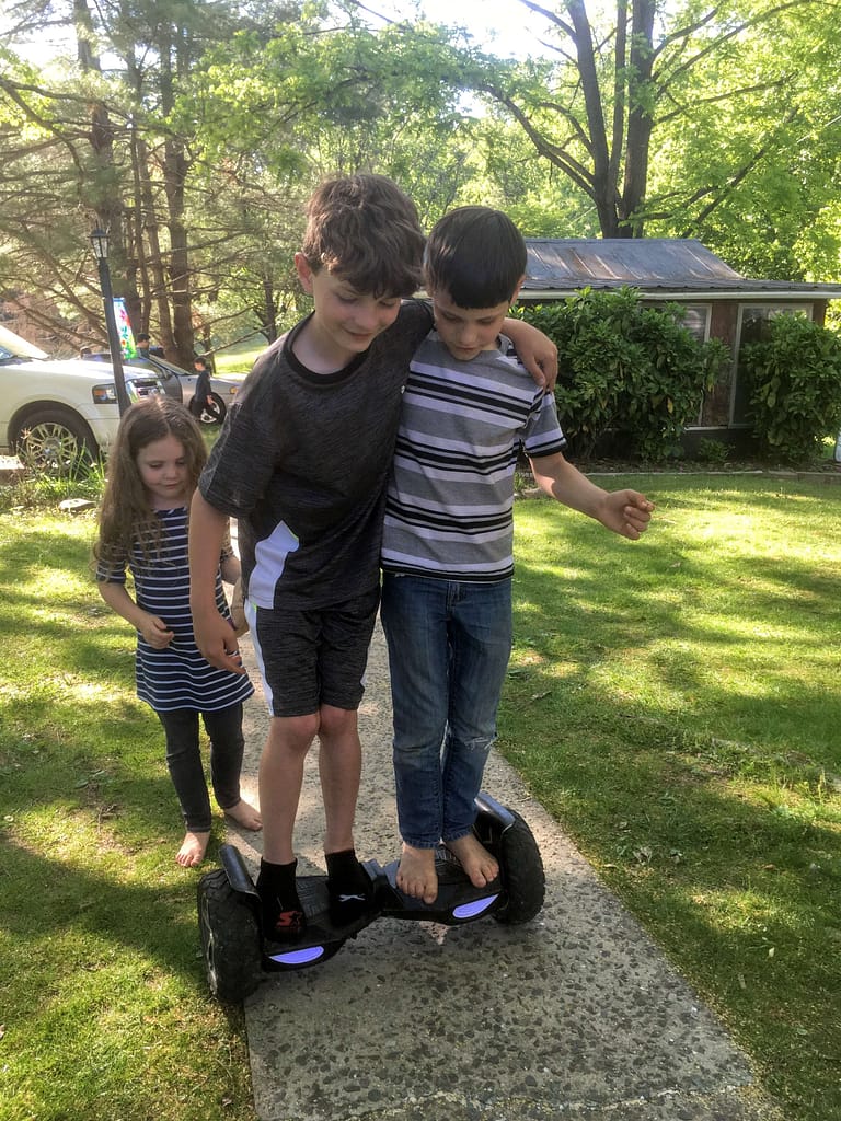 two boys riding on one hooverboard