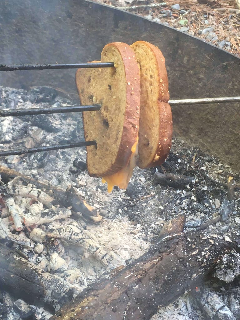 a grilled cheese sandwich being roasted over a campfire