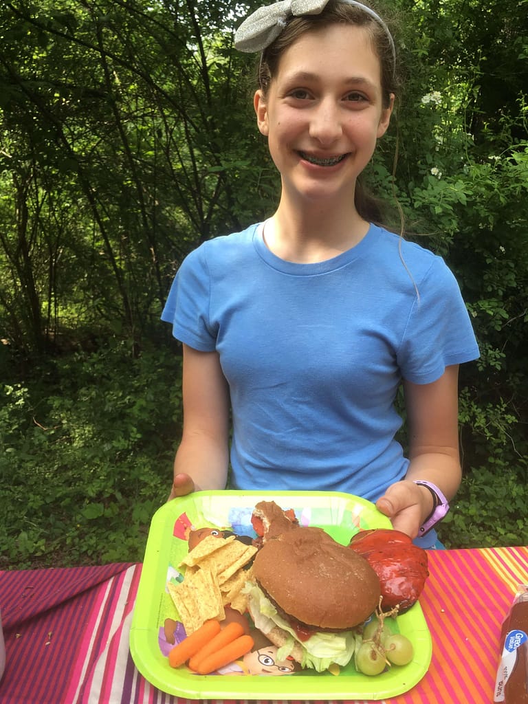 13 year old girl with her plate of food camping