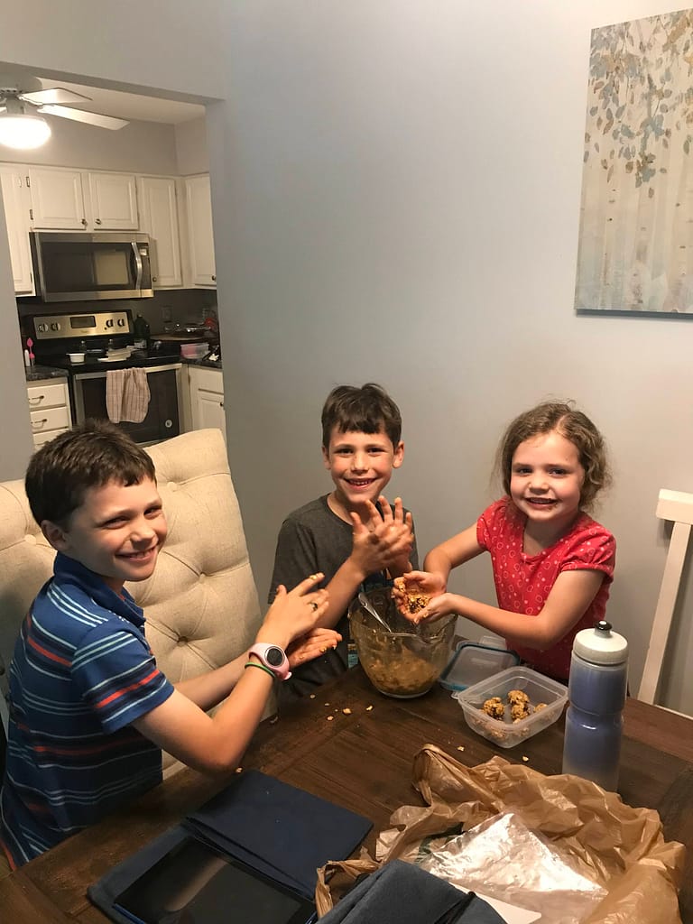 3 children make oatmeal balls at the kitchen table