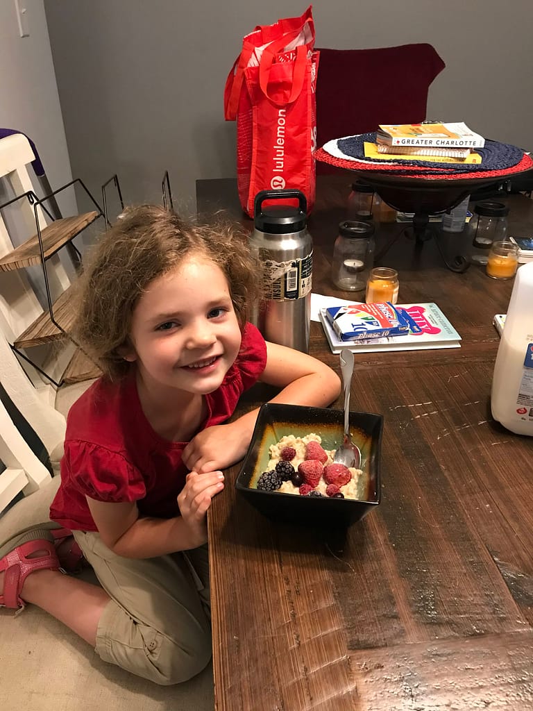 5 year old eats a bowl of oatmeal with berries in it