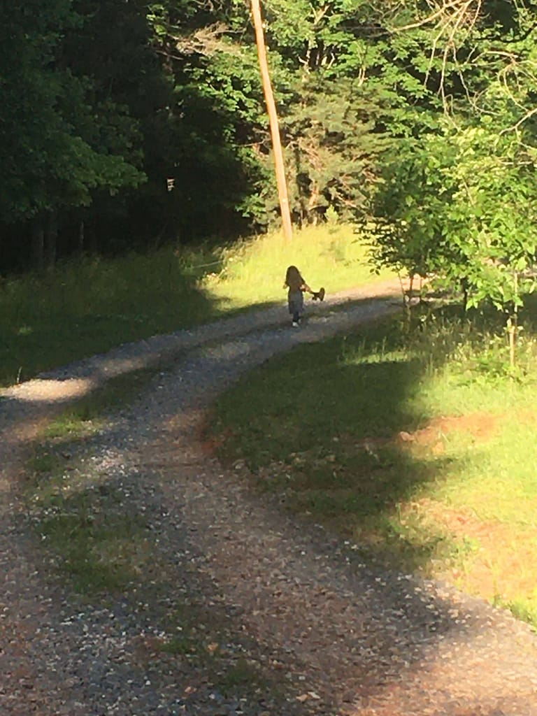 5 year old carrying weed eater down a dirt driveway