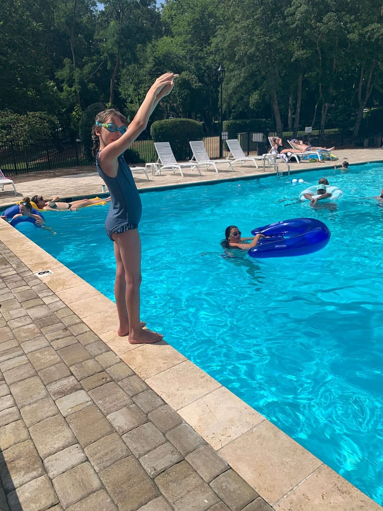 an 11 year old girl ready to dive into the pool