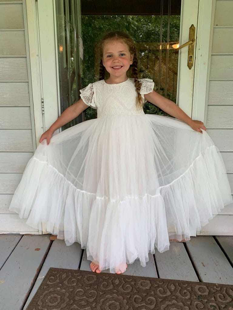 6 year old holding her white dress out