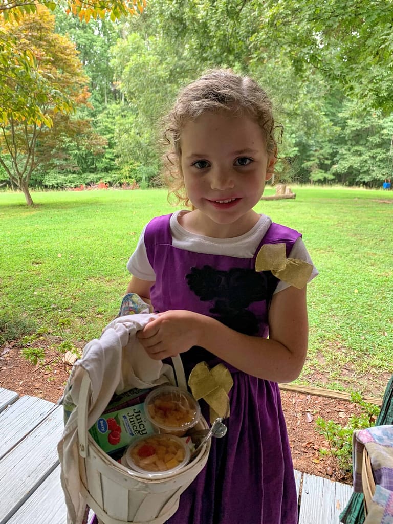 6 year old girl showing her picnic basket of food at a calpurnia tate type picnic