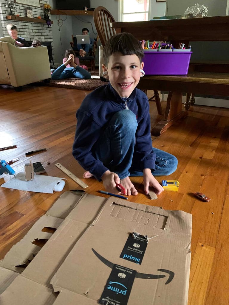 8 year old making things out of cardboard while listening to an audio book