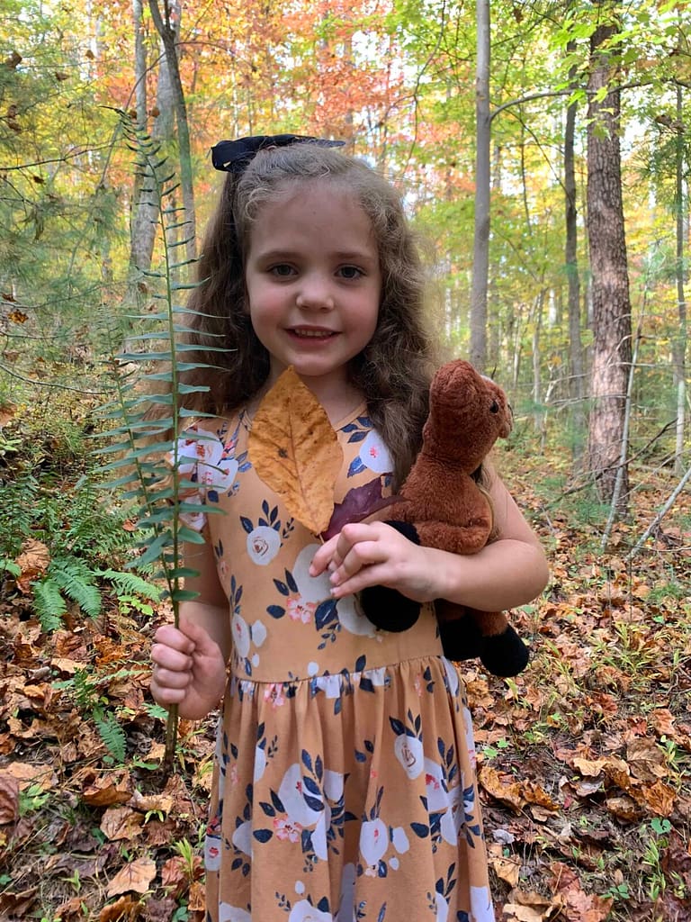 6 year old holding ferns in the woods