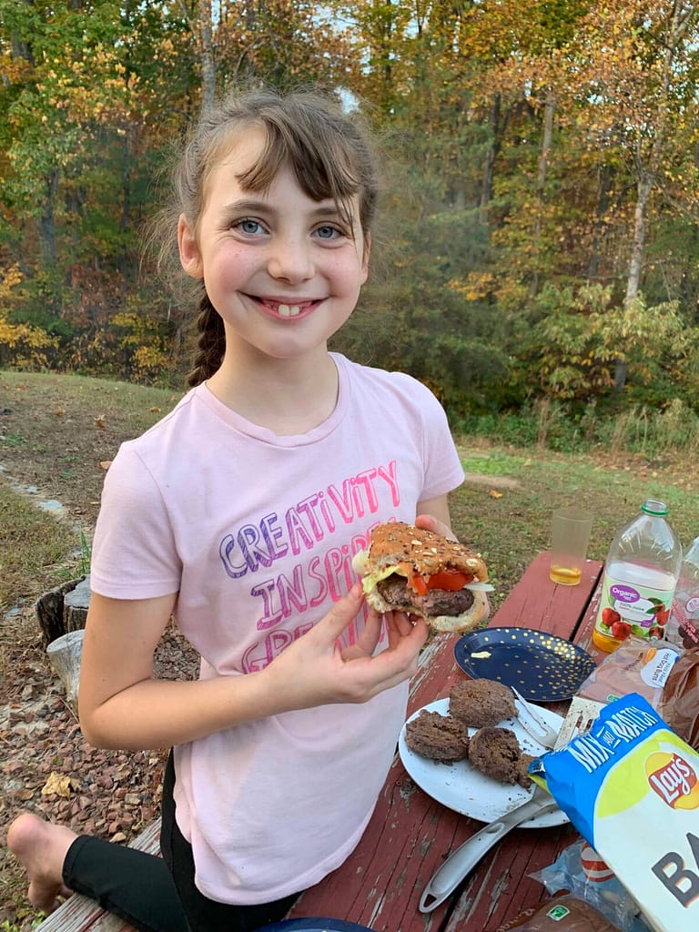 11 year old showing her hamburger and smiling