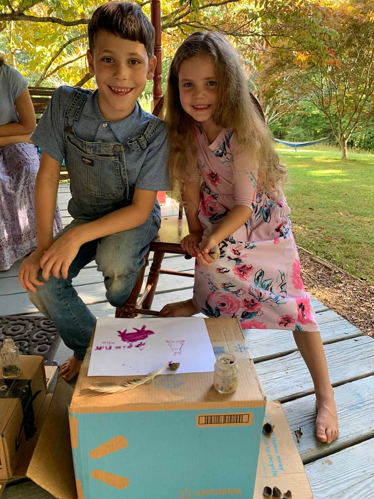 brother and sister using poke berries for ink and drawing with it outside