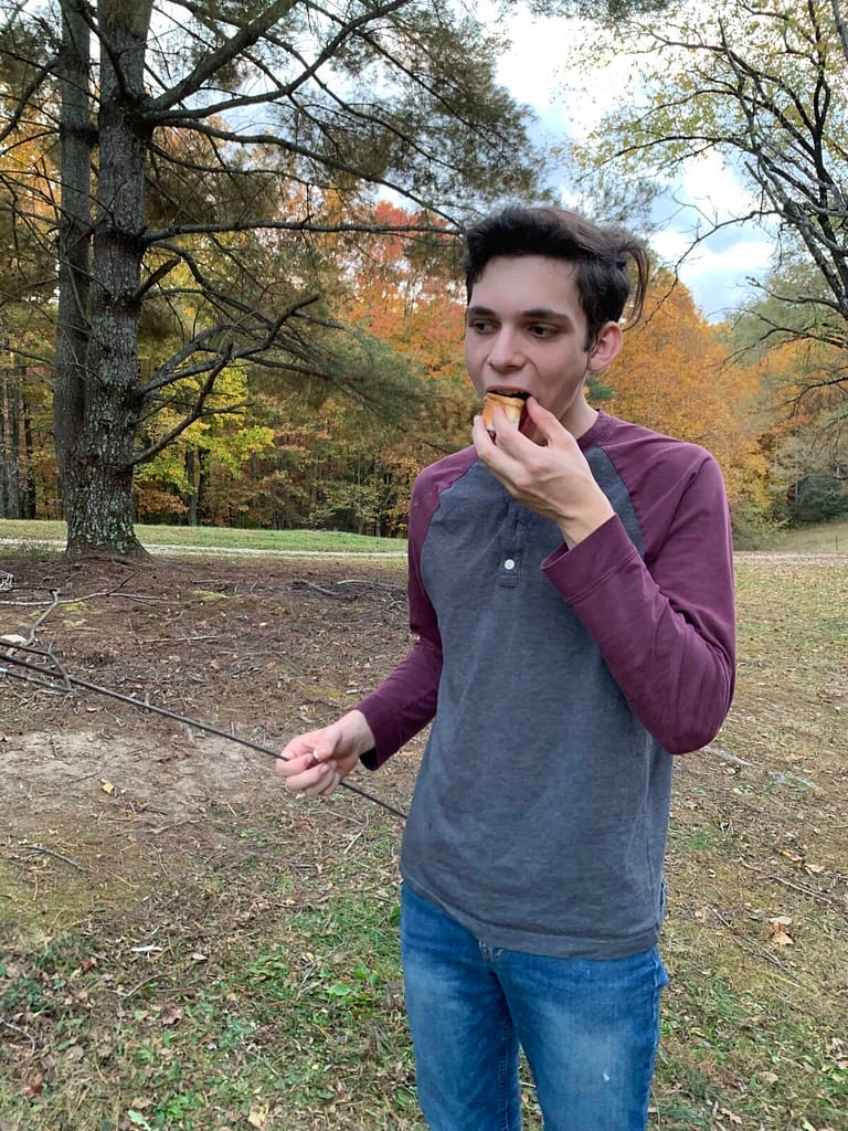 teen boy eating a roasted marshmallow