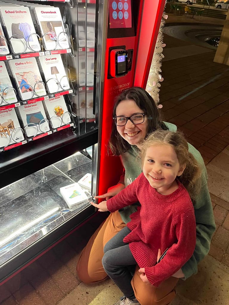 2 girls donating to light the world giving machine