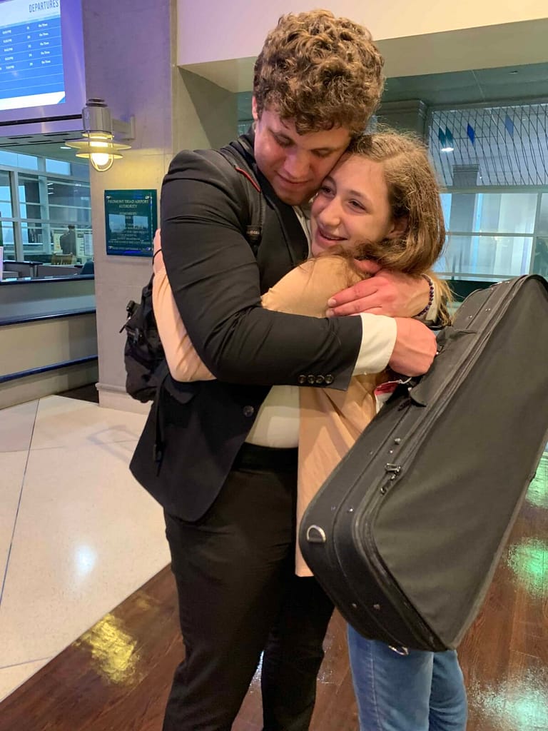 big brother hugging sister off the airplane