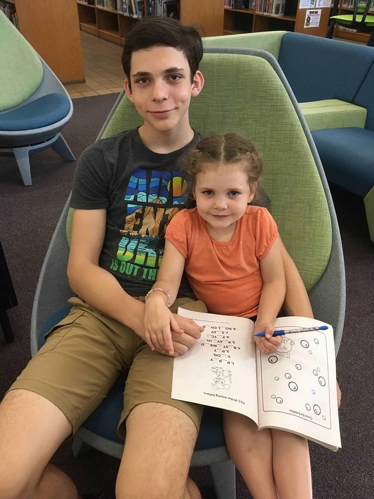 15 year old brother coloring with 5 year old sister in the libary