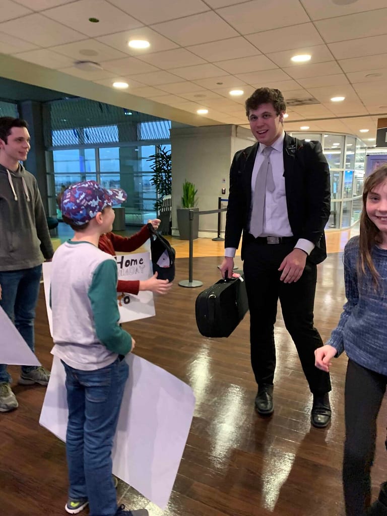 brother greeting siblings at the airport