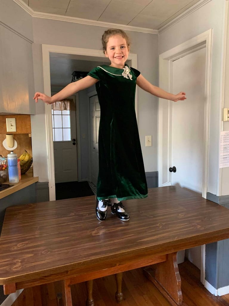 6 year old in green dress tap dancing on the table