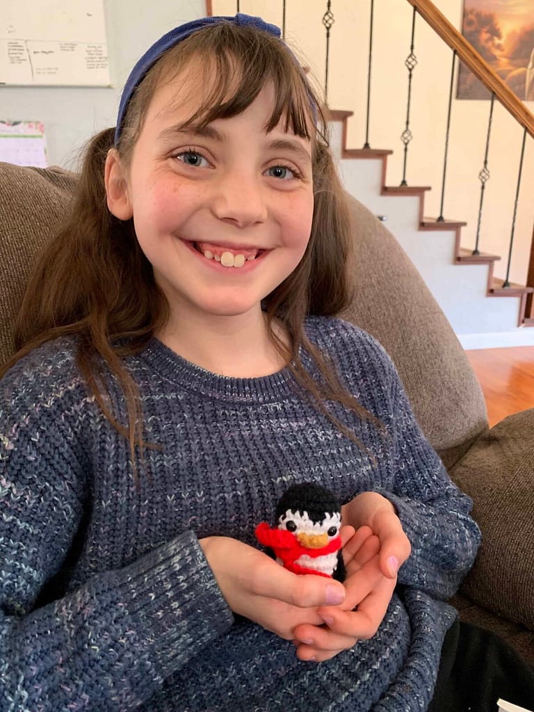 12 year old girl holding crocheted penguin