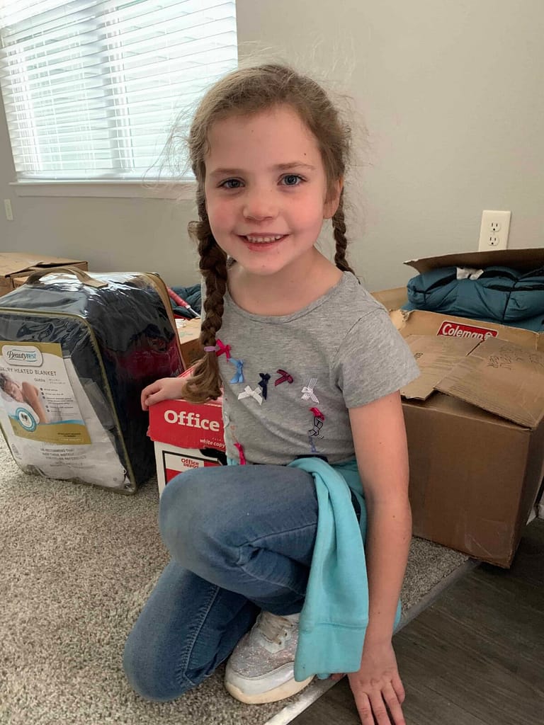 6 year old girl crouching on the carpet and smiling with braids