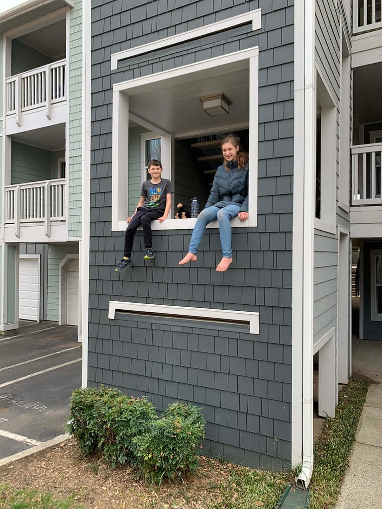 two kids sitting at apartment window