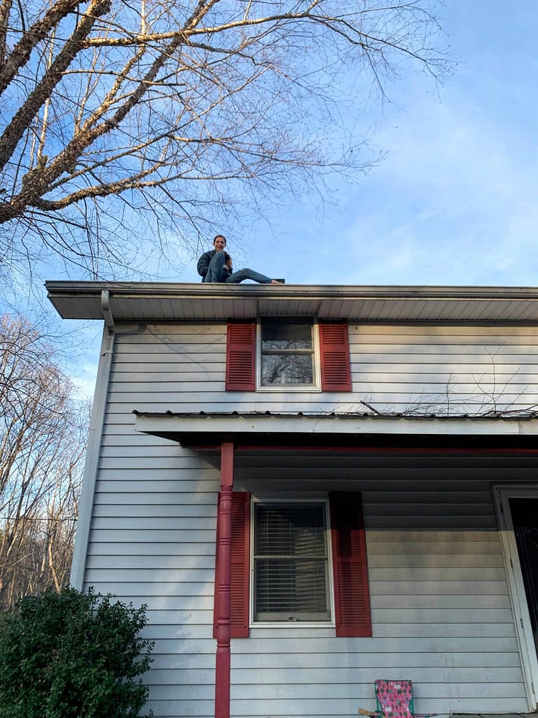 girl cleaning gutters on a two story roof