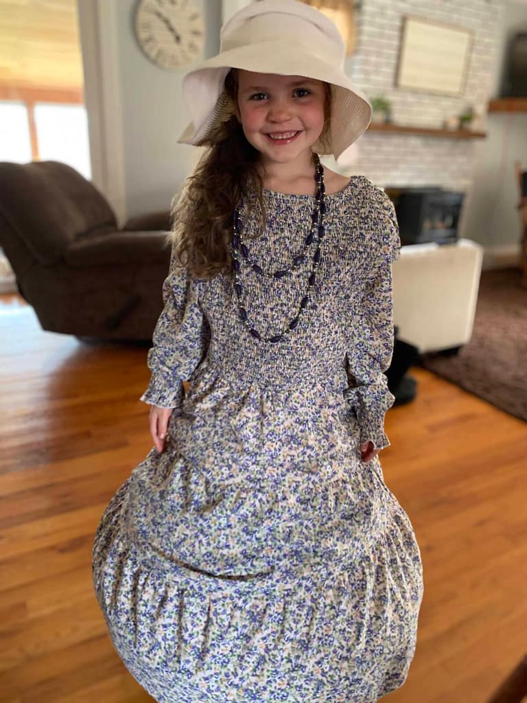 little girl dressed up in her mom's dress and hat
