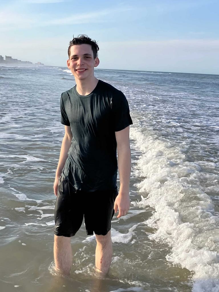 16 year old boy wearing black swimsuit at the beach