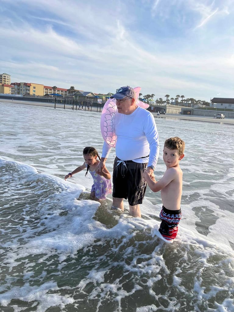 grandpa and 2 kids wading into the water