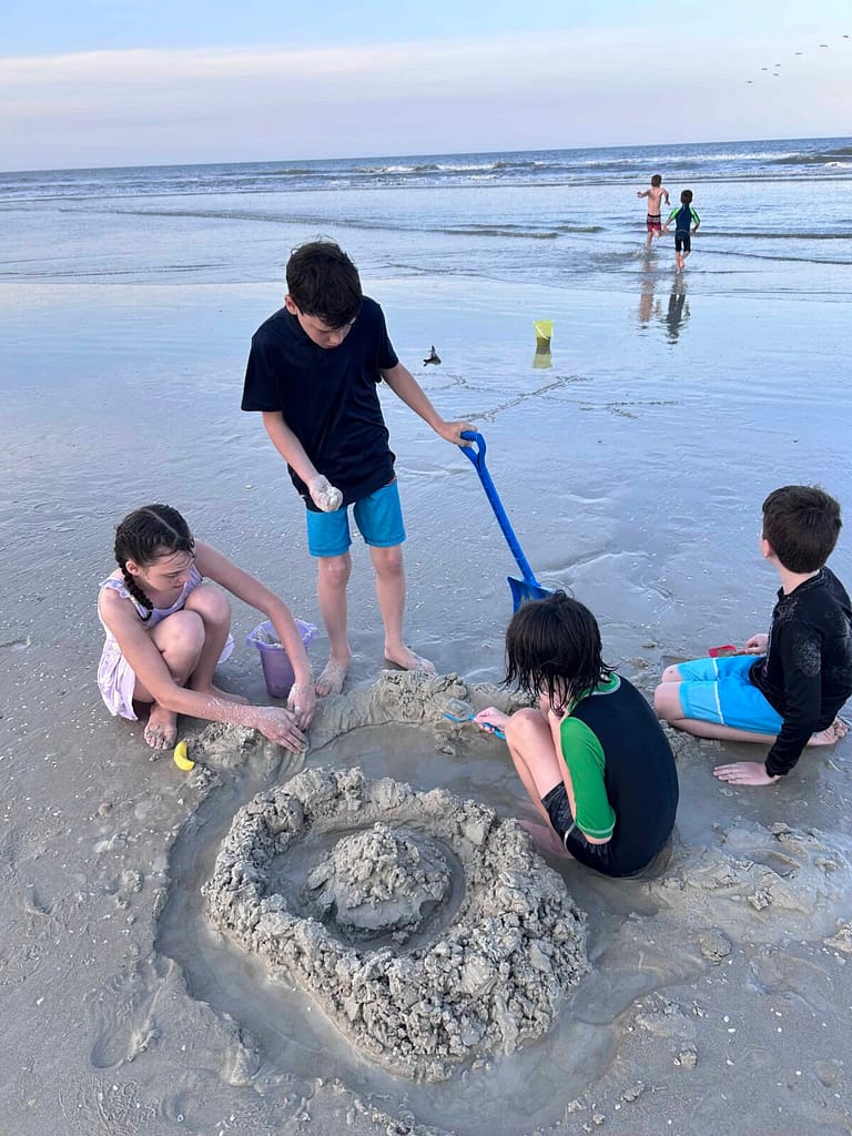 4 young kids making moats at the beach