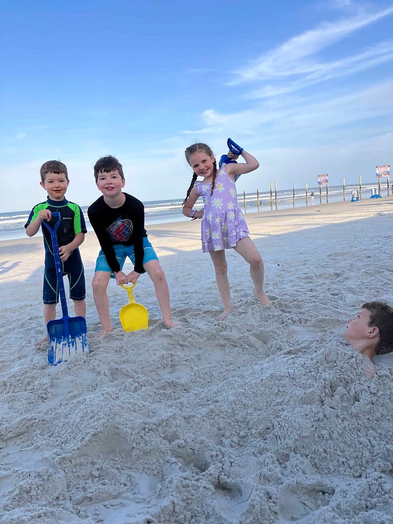 kids burying a kid at the beach