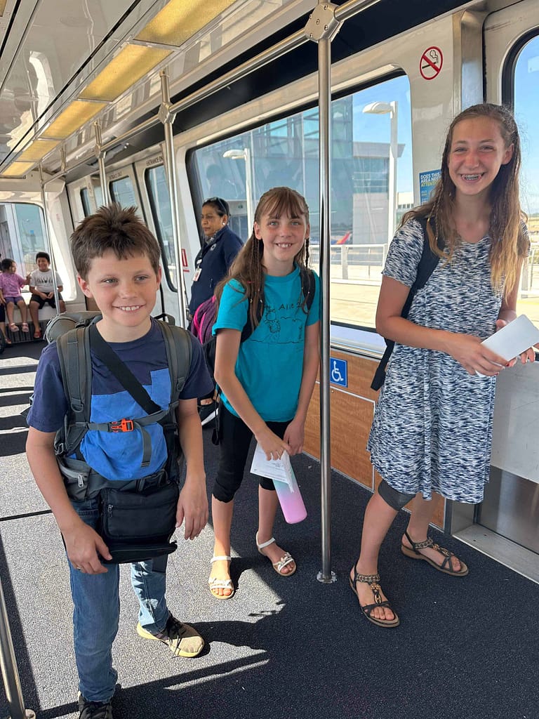 3 kids on a sky tram at an airport