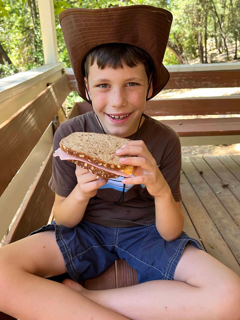 boy eating sandwich with cowboy hat on