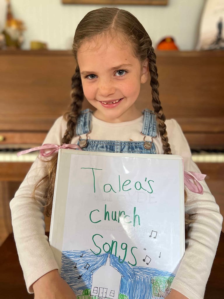 7 year old girl holding a songbook she made
