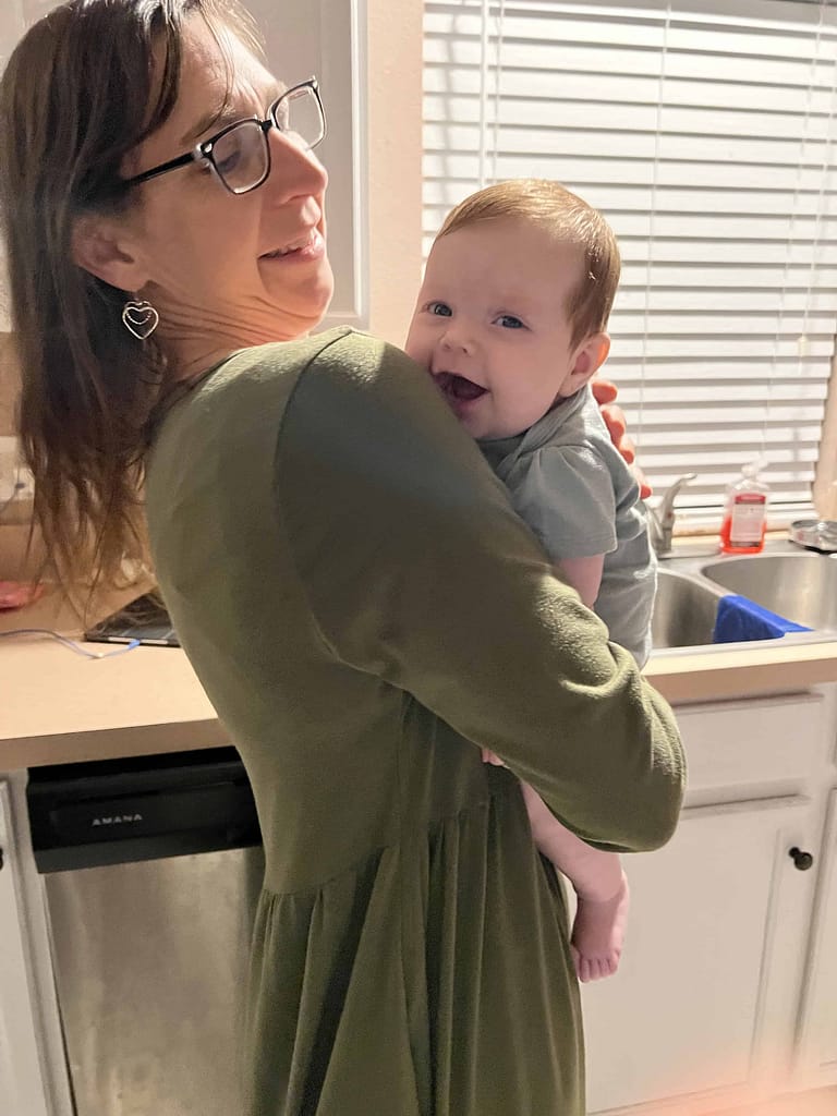 mom holding 2 month old baby girl smiling