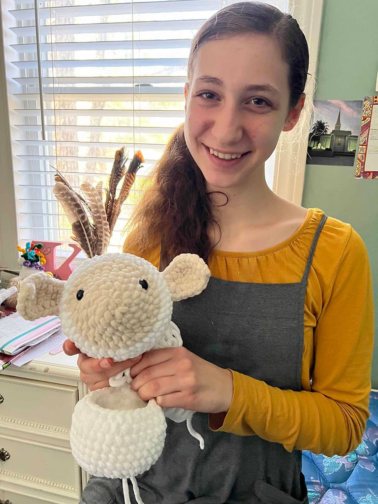 teen girl crocheting a lamb doll