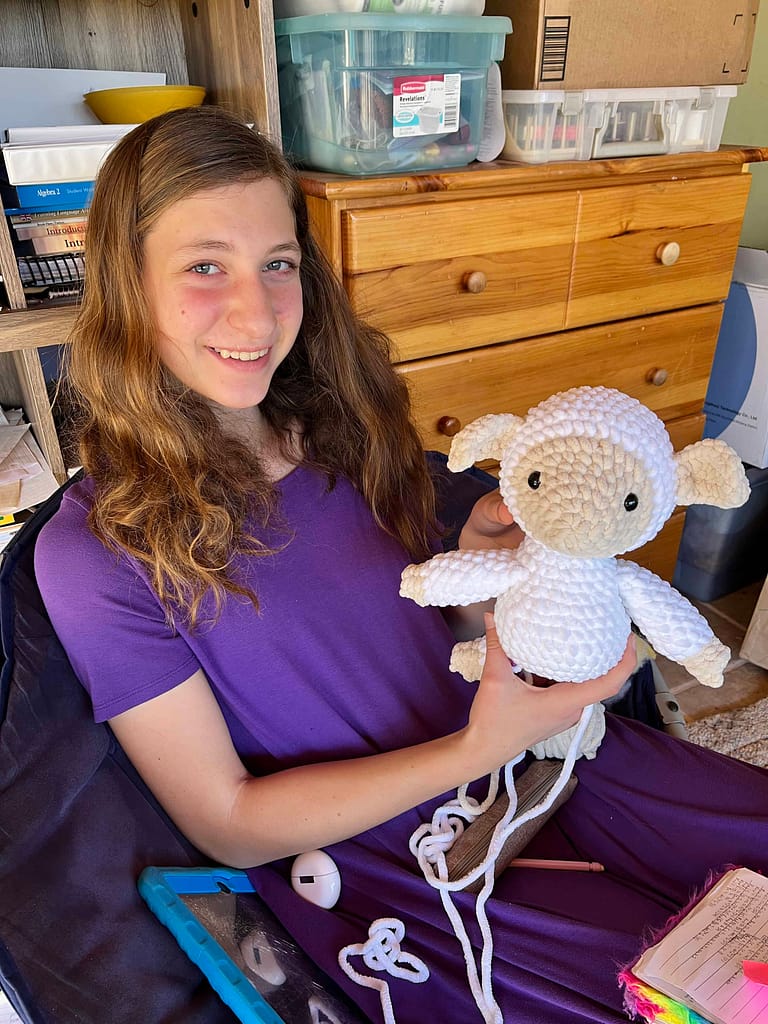 teen girl crocheting a lamb doll