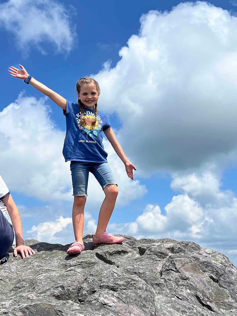 7 year old girl standing on top of a boulder