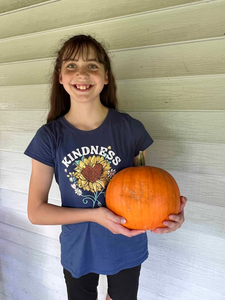 13 year old girl holding pumpkin she grew