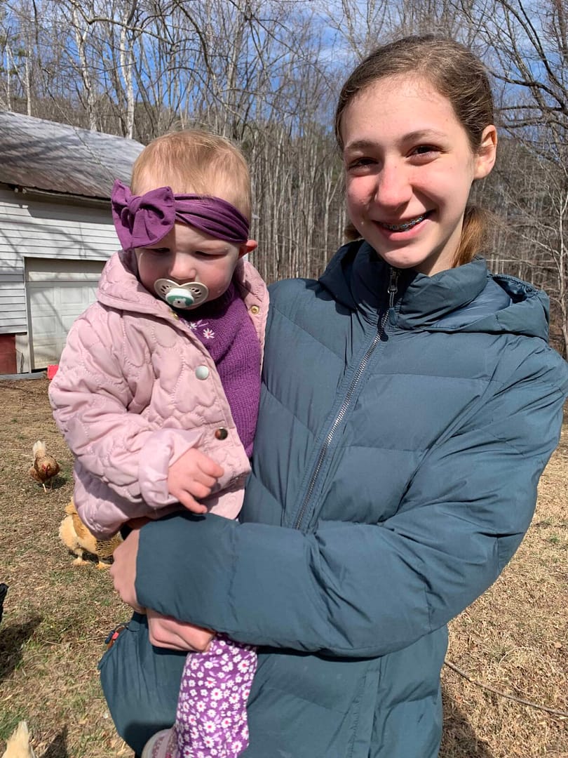 13 year old holding 1 year old in coats outside