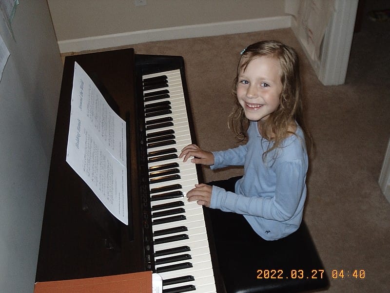 a young girl sitting at a digital piano teaching herself to play the piano