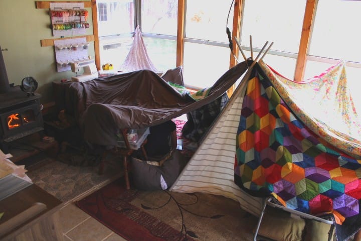 A big blanket fort kids made in a sunroom