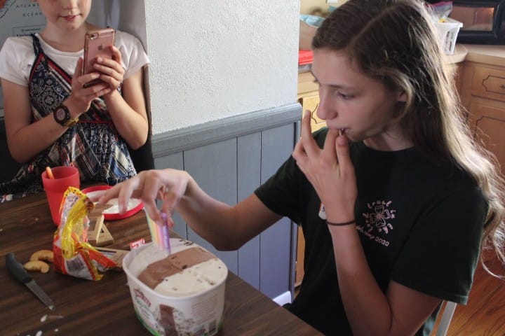 girl licks her fingers as she pulls candles out of her ice cream carton