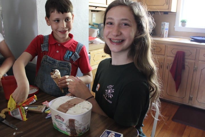 girl smiles about blowing out candles and little brother watches her